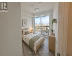 A bedroom with a bed, nightstand, and a window overlooking a cityscape.