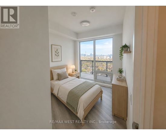 A bedroom with a bed, nightstand, and a window overlooking a cityscape.