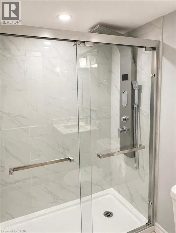 A glass shower stall with a silver handle and a silver grab bar.