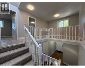 A well-lit, spacious interior of a house with a staircase leading to the upper floor.