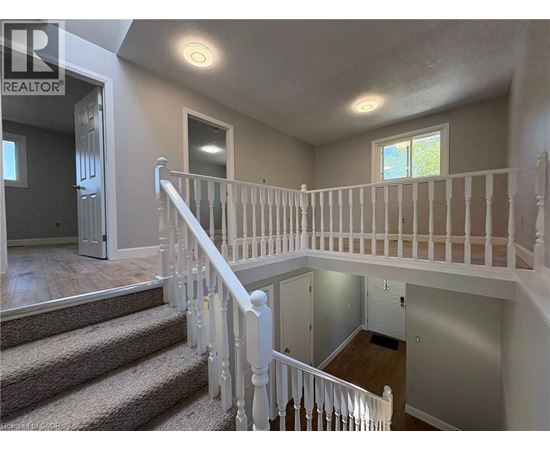 A well-lit, spacious interior of a house with a staircase leading to the upper floor.