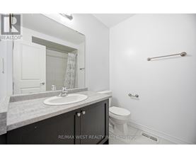 A bathroom with a toilet, sink, and mirror.