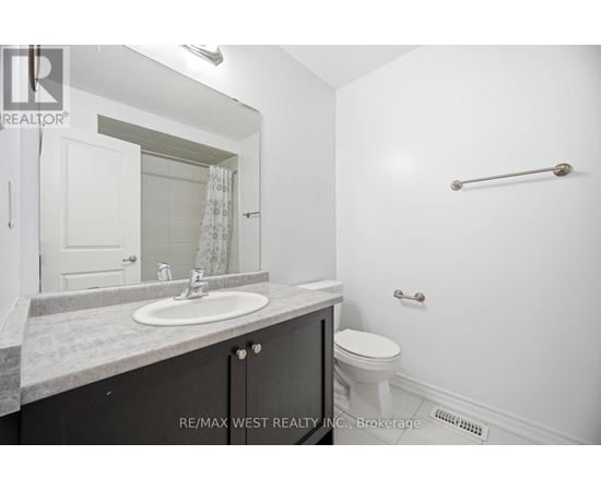 A bathroom with a toilet, sink, and mirror.