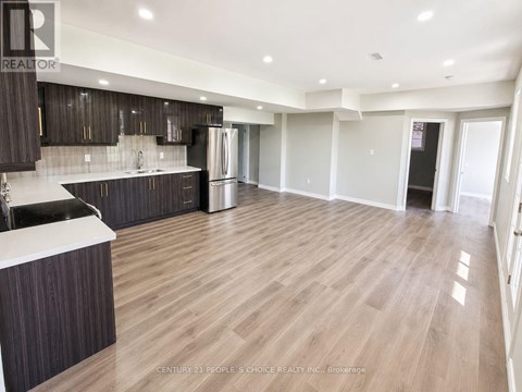 A spacious kitchen with dark wood cabinets and a white countertop.