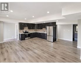 A spacious kitchen with wooden flooring and modern appliances.