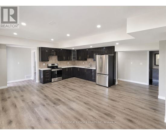 A spacious kitchen with wooden flooring and modern appliances.
