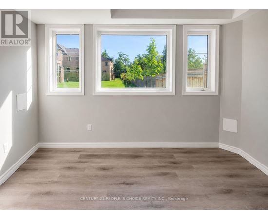 A room with a large window showing a view of a house and trees.