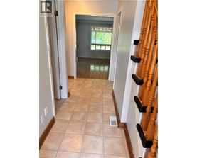 A hallway with a tile floor and a wooden staircase.