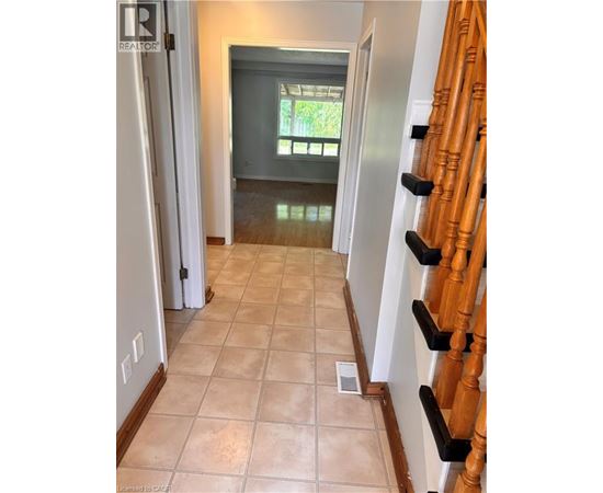 A hallway with a tile floor and a wooden staircase.