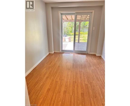 A room with wooden floors and a sliding glass door leading to a backyard.