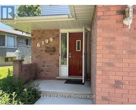 A red door with the number 6199 on the brick wall.