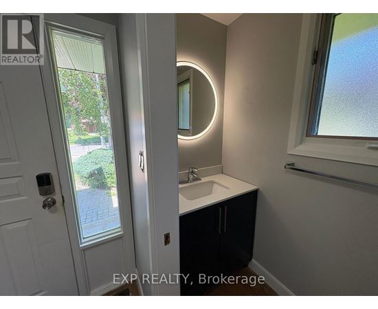 A bathroom with a white door, a round mirror, and a window.