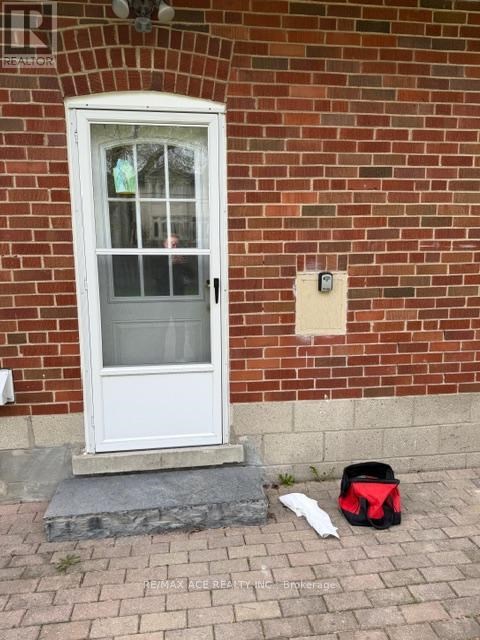 A white door with a glass window is on a red brick wall.