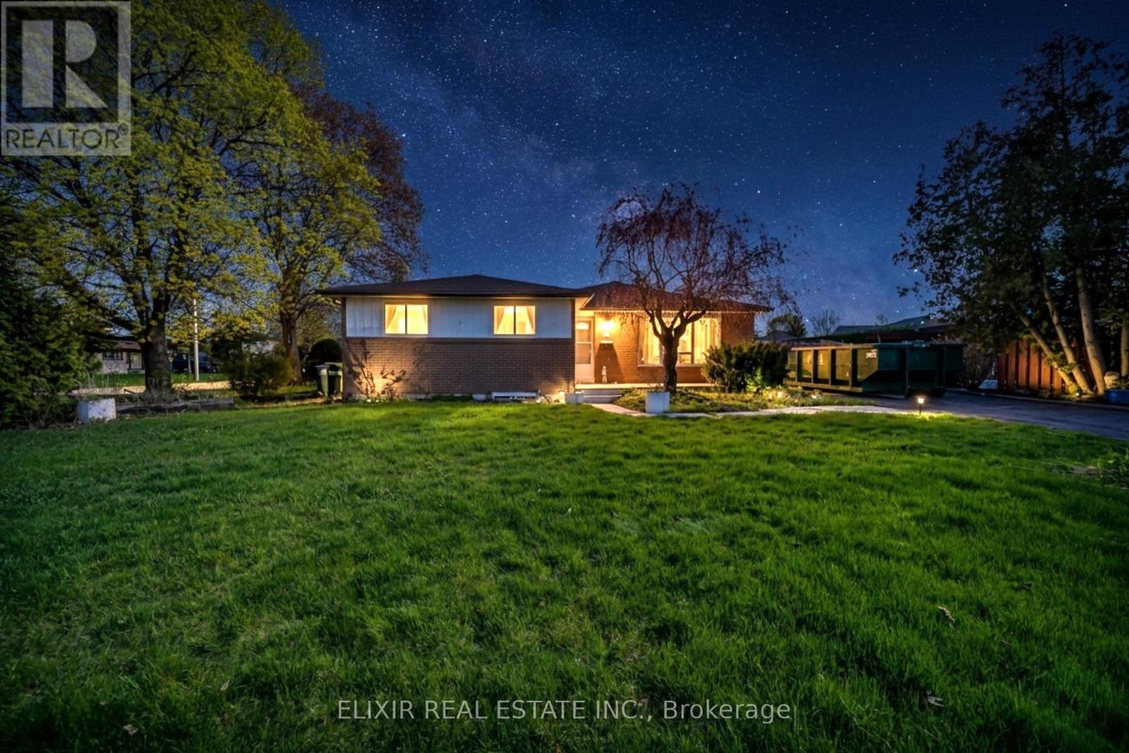 A nighttime photo of a house with the logo "R REALTOR" in the upper left corner.