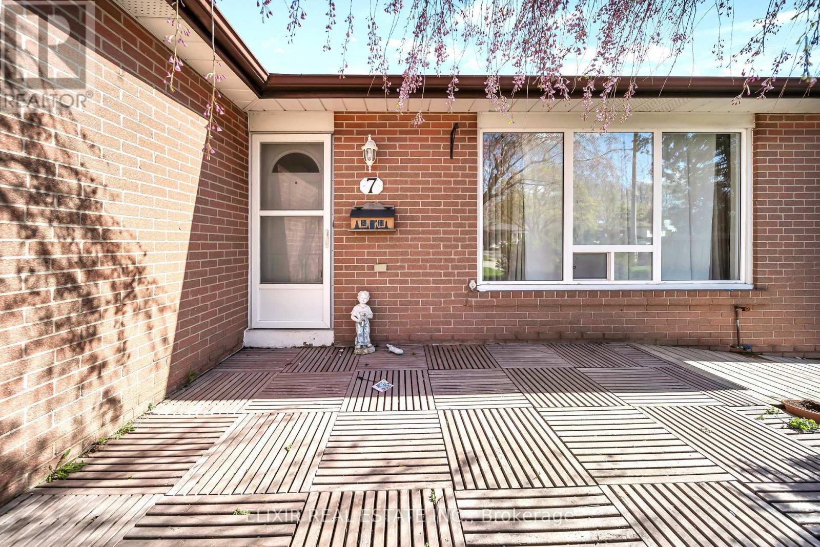 A small white dog is standing on a brick patio.