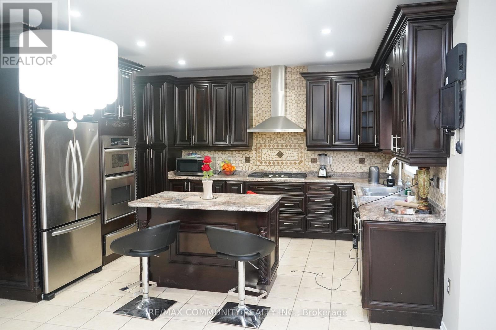 A modern kitchen with dark wood cabinets and stainless steel appliances.