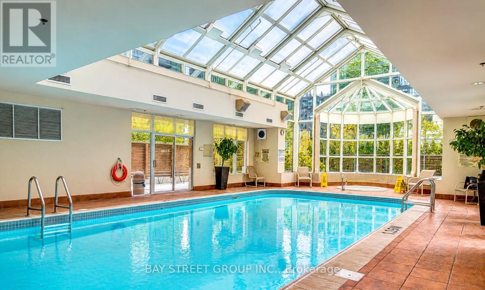 A swimming pool inside a building with a glass ceiling.