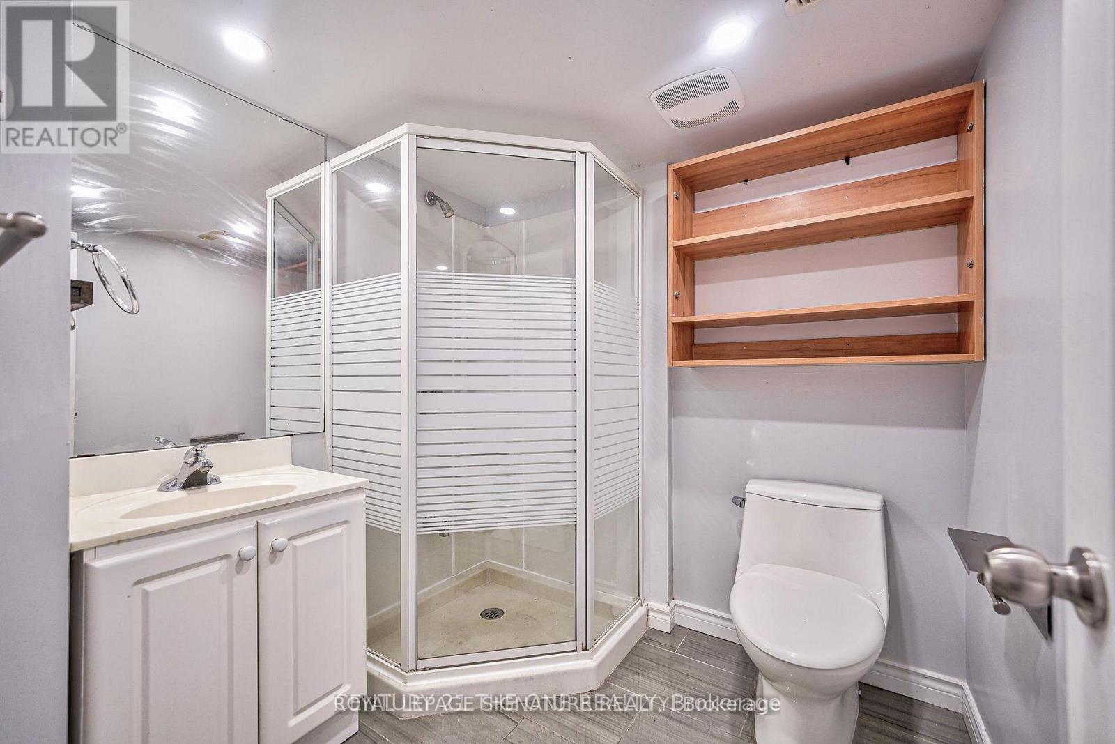 A white bathroom with a walk in shower and a toilet.