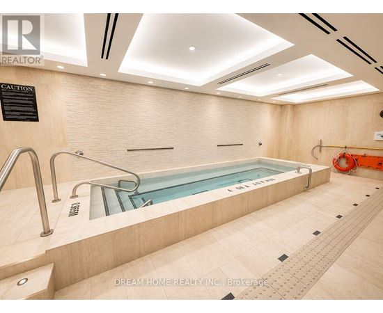 A swimming pool in a room with a caution sign on the wall.
