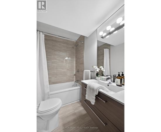 A modern bathroom with a white toilet, a white sink, and a white shower curtain.