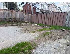 A backyard with a wooden fence and a dirt area in the middle.
