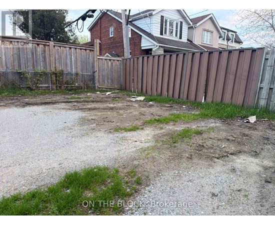 A backyard with a wooden fence and a dirt area in the middle.