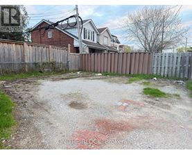 A backyard with a dirt area and a wooden fence.
