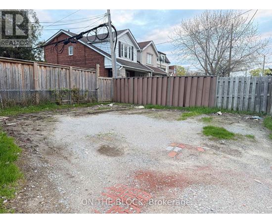 A backyard with a dirt area and a wooden fence.