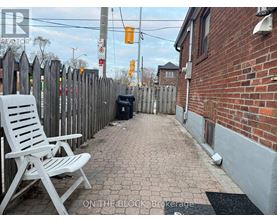 A white chair is on a brick walkway.
