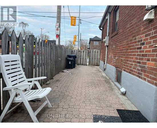 A white chair is on a brick walkway.