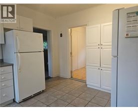 A white refrigerator is in a kitchen with a white door and a white cabinet.