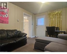 A living room with a black couch, a grey ottoman, and a black chair.