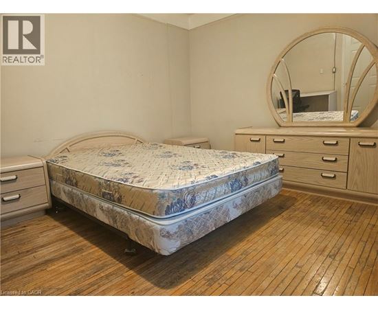 A bedroom with a round mirror and a bed with a floral patterned bedspread.