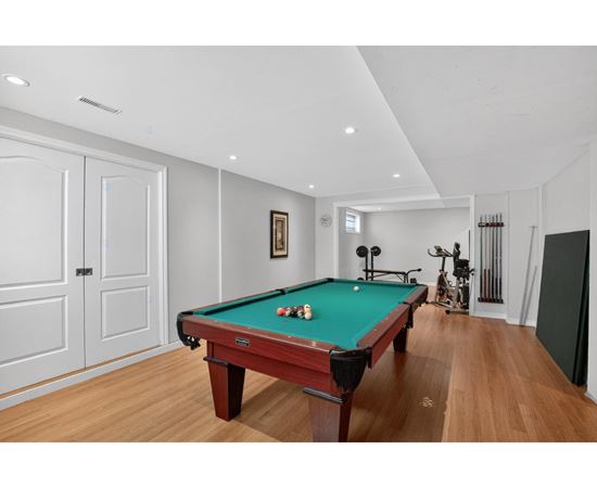 A pool table is in the middle of a room with a wooden floor.
