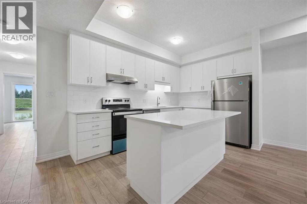 A modern kitchen with white cabinets and a wooden floor.