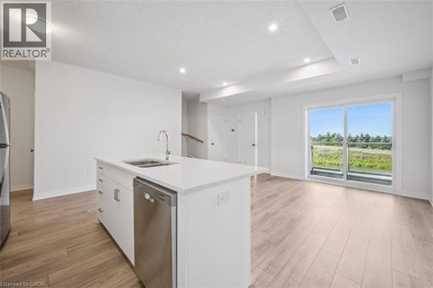 A modern kitchen with white cabinets and a large window.
