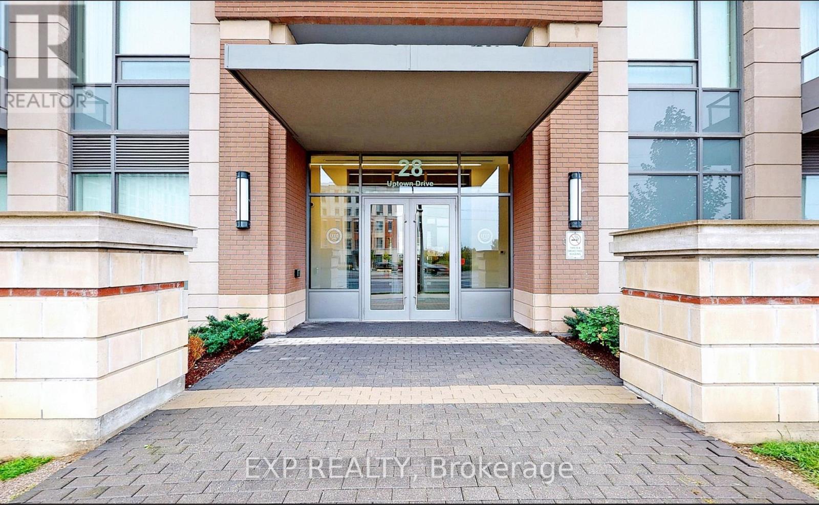 The entrance to a building with a glass door and a brick facade.