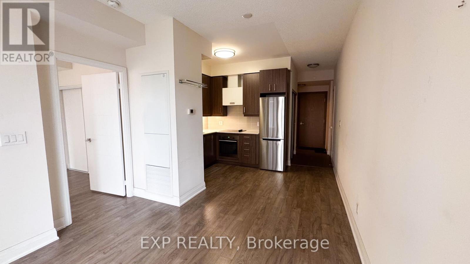 A kitchen area with a refrigerator, sink, and cabinets.