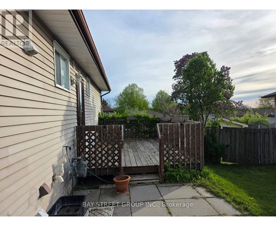 A backyard with a wooden deck and a tree.