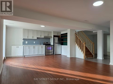 A spacious kitchen with white cabinets and a staircase in the background.