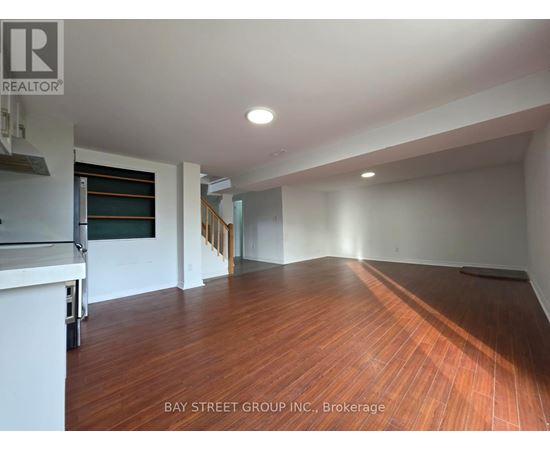 A spacious room with wooden flooring and white walls.