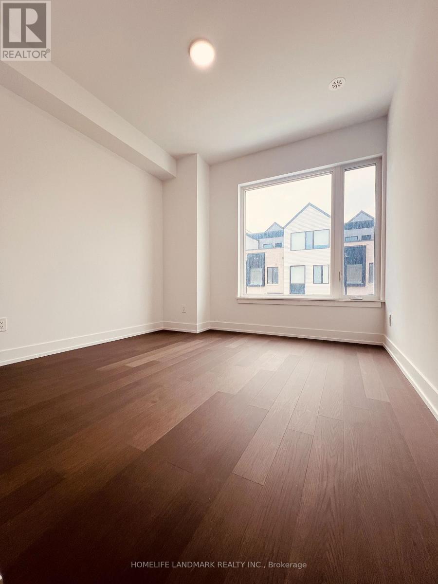 A room with wooden flooring and a large window showing a view of buildings outside.