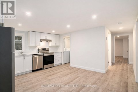 A spacious kitchen with white cabinets and a wooden floor.