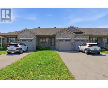 Two cars are parked in front of a brick house with a sign that says REALTOR.