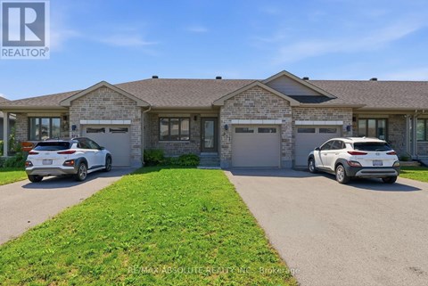 Two cars are parked in front of a brick house with a sign that says REALTOR.