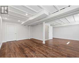 A room with wooden floors and white walls, with a ceiling that has exposed beams.