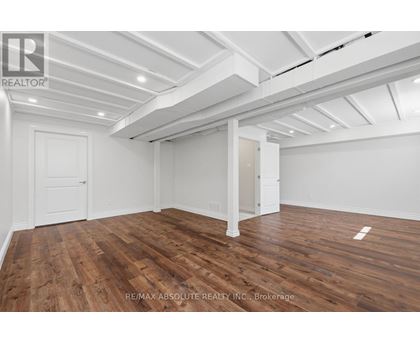 A room with wooden floors and white walls, with a ceiling that has exposed beams.