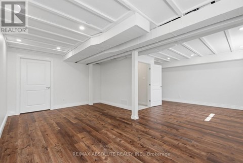 A room with wooden floors and white walls, with a ceiling that has exposed beams.