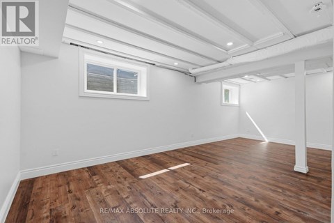 A room with wooden flooring and white walls, with a window and a door frame visible.