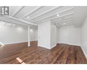 A room with wooden flooring and white walls, with a door and a window.
